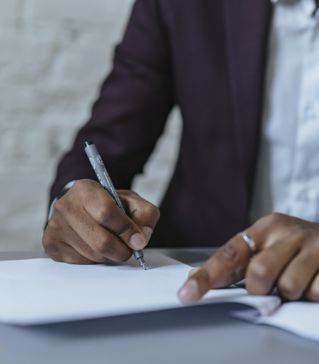 A Man Writing on White Paper using a Black Pen